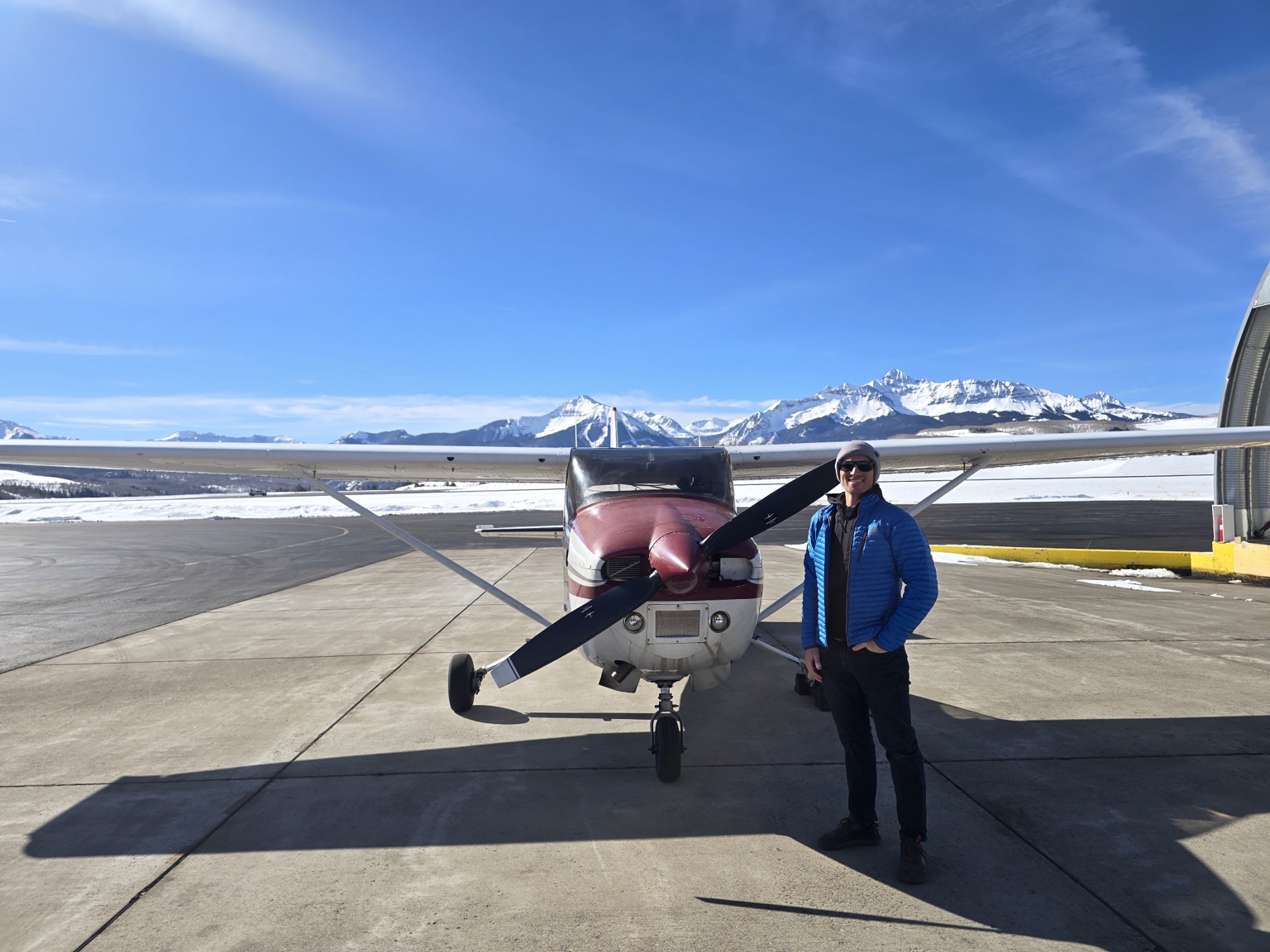 Cole VandenBerg standing beside a Cessna with snow-covered Colorado mountains behind him